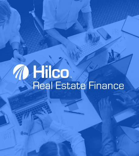 Hilco Real Estate Finance - team working around a shared desk with laptops and documents