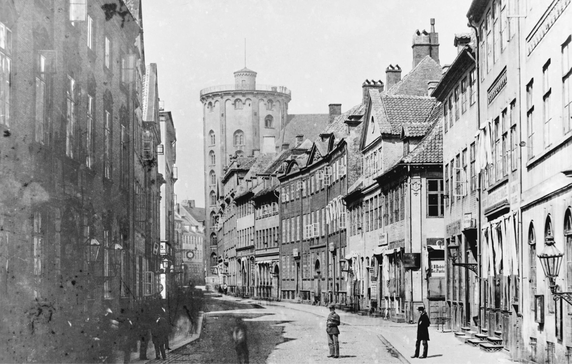 Historic black-and-white photograph of Købmagergade in Copenhagen with the Round Tower in the distance